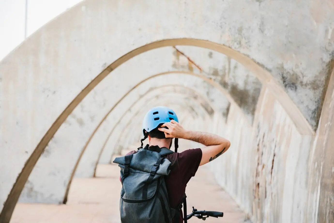 Rear view of a cyclist putting on his helmet.